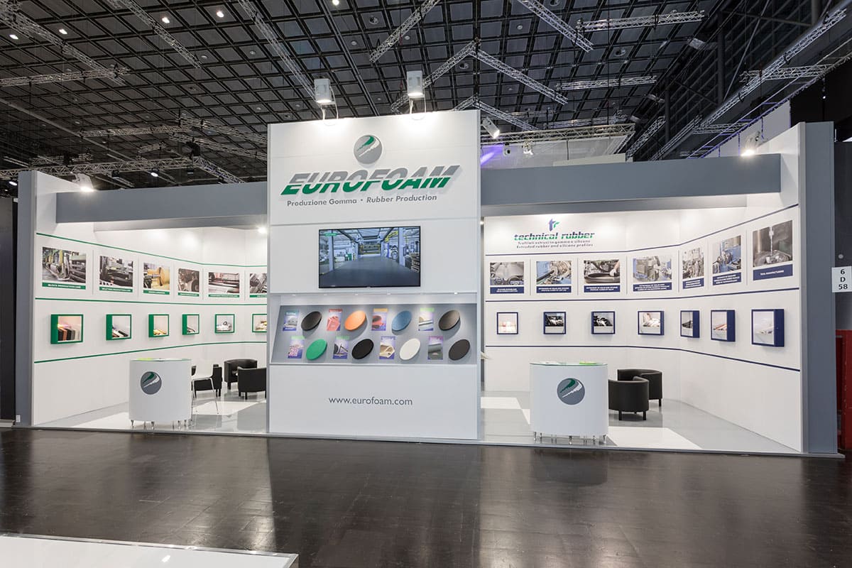 L' immagine raffigura un caso reale di allestimento fieristico: l' allestimento dello stand Eurofoam Technical Rubber realizzato in occasione di una precedente edizione della fiera K Kappa di Düsseldorf. La foto mostra una vista panoramica presa da Sud nella quale si nota la scelta di progettazione e realizzazione in base alla quale è stata ricreata una parete curva interna che raccorda i prodotti forniti dalle due aziende che lavorano in sinergia tra loro.
