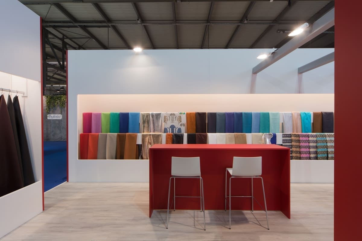 Come le precedenti, anche questa immagine raffigura il caso reale dell' allestimento stand Moden Pelli realizzato in occasione di una precedente edizione di Linea pelle di Milano. Lo stand è qui ripreso da una diversa angolazione ripetto all' immagine precedente e ci mostra un prospetto forntale dell' ingresso che sottolinea il carattere rigoroso delle forme e le cromie decise e pure.