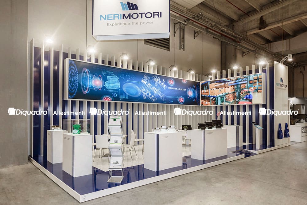 Allestimenti fieristici Mec Spe Bologna casi reali: l' allestimento stand realizzato per Neri Motori visto da Ovest L' immagine raffigura un caso reale di allestimento fieristico: l' allestimento dello stand Neri Motori realizzato da Diquadro in occasione di una precedente edizione della fiera Mec Spe di Parma. La foto mostra l' allestimento dello stand visto da Ovest. In particolare, mostra la parte di fondo lavorata ad elementi verticali ritmicamente distribuiti, all' interno dei quali sono stati inseriti la grafica retroilluminata e il ledwall. Si vedono, inoltre, l' esposizione dei prodotti e gli abbinamenti cromatici che caratterizzano in maniera peculiare questo allestimento fieristico.