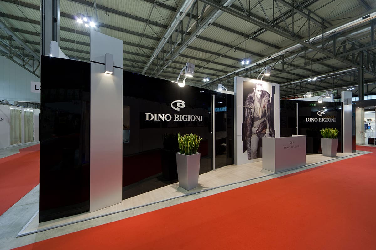 L'immagine raffigura un caso reale di allestimento fieristico: l'allestimento dello stand Dino Bigioni realizzato per fiera Micam di Milano. L'immagine ci mostra una vista esterna dello stand. In particolare, ci mostra l'allestimento ripreso di fronte.