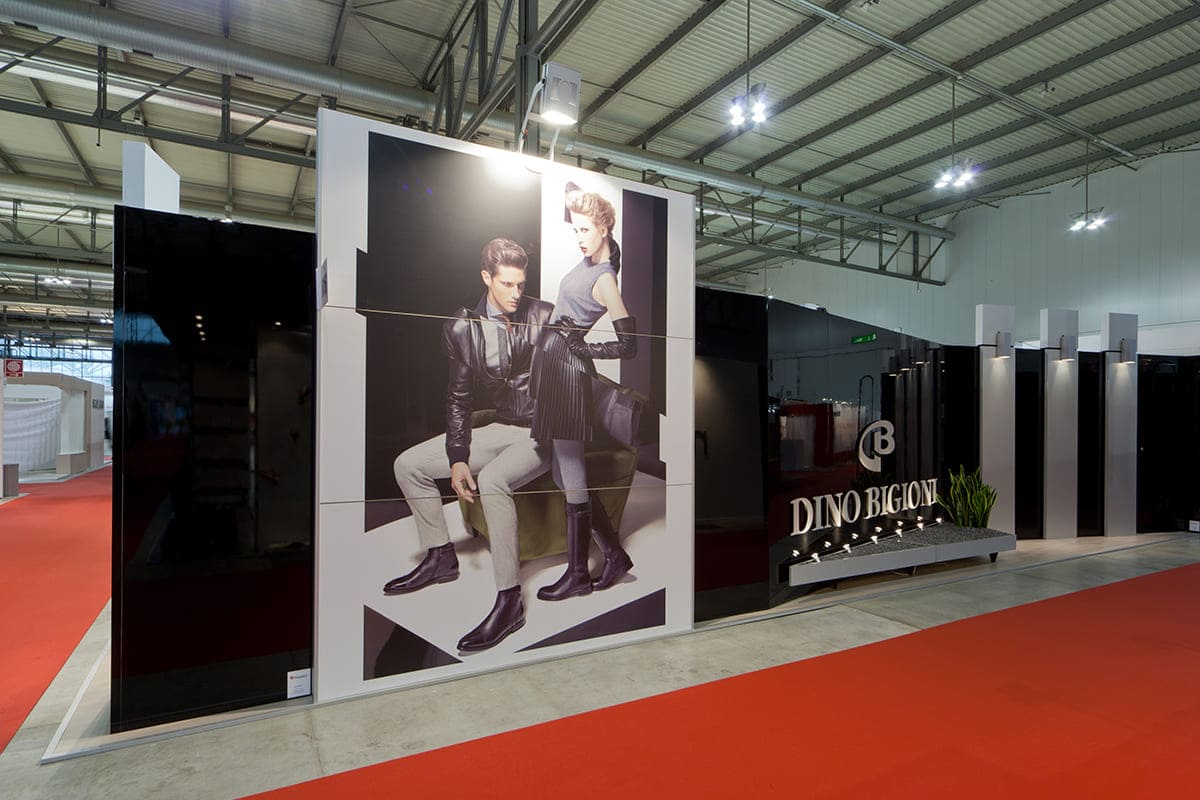 L'immagine raffigura un caso reale di allestimento fieristico: l'allestimento dello stand Dino Bigioni realizzato per fiera Micam di Milano. L'immagine mostra lo stand realizzato, ripreso esternamente dal lato Est.