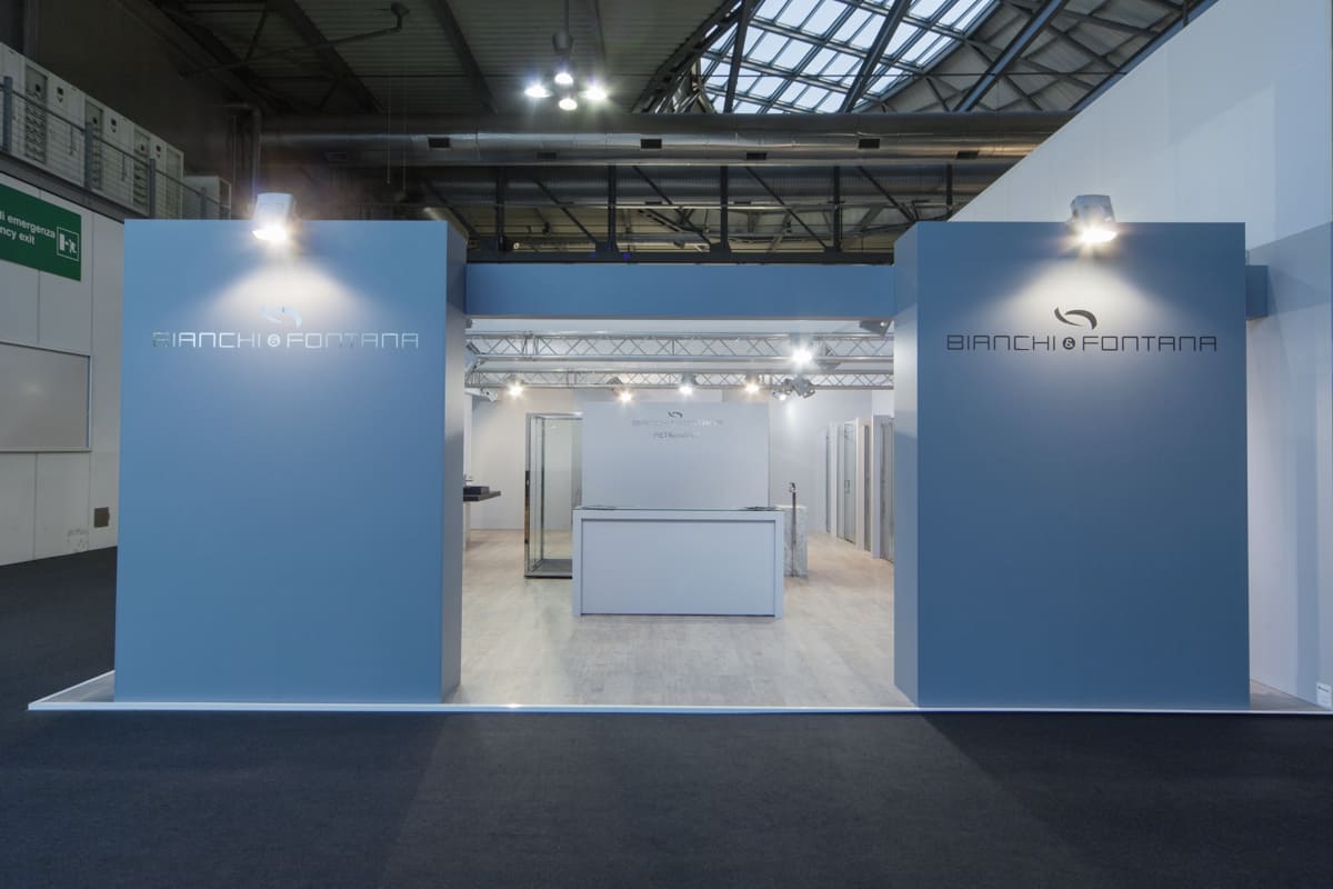 L' immagine mostra un allestimento realizzato da Diquadro per fiera Salone del Mobile di Milano: lo stand Bianchi & Fontana. L' azienda committente lavora l' acciaio inox e produce cabine doccia arredo dal pregiato design. Lo stand è stato allestito in stile industriale, facendo uso di tavolame grezzo, pareti grigio cemento, tralicci in metallo a vista, lampade per illuminazione di capannoni. Il concept seguito per nell' allestimento stand Bianchi e Fontana è stato sia esporre i prodotti sia parlare del materiale acciaio con un linguaggio architettonico puro e semplice come l' acciaio stesso.